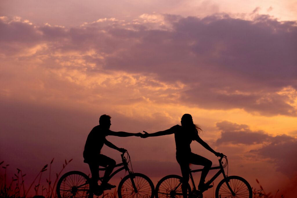 A couple biking hand in hand symbolizing connection in a fast-moving world. Relationships Matter.